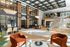 Modern apartment lobby with velvet seating, glass staircase, wood accents, and natural light.