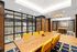 Stylish conference room with natural wood tables, yellow chairs, and floor-to-ceiling windows.
