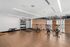 Modern mezzanine-level fitness area with stationary bikes, weights, and a training station overlooking a gym.
