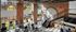 Spacious gym with cardio machines, a stairwell, large windows, brick walls, and a mural reading "Work Sweat Achieve."