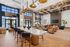Stylish lounge area with modern light fixtures, cozy seating, wood flooring, and a fireplace beneath a mounted TV.
