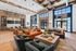 Expansive resident lounge featuring modern lighting, a central bar area, and a mix of soft seating with natural light streaming through tall windows.