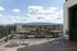 Rooftop patio area overlooking the San Jose cityscape, with mountains in the distance, modern apartment buildings below, and open sky above.