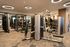 Spacious gym featuring strength training machines, weight racks, and mirrored walls, all set in a well-lit room with modern lighting and carpeted flooring.