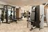 Modern fitness center featuring a variety of strength training machines, free weights, and benches, with bright lighting and a spacious layout.