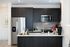 Modern kitchen with dark cabinetry, white countertops, stainless steel appliances, a microwave, and a tile backsplash, offering a clean and stylish look.