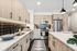 A modern kitchen featuring light wood cabinetry, white countertops, stainless steel appliances, pendant lighting, and a tile backsplash, accented by a patterned rug and everyday kitchen essentials.