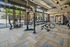 Modern gym with weightlifting equipment, squat racks, and large windows offering natural light and outdoor views.