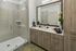 Modern bathroom with a large wooden vanity, dual sinks, a wide mirror, and a glass-enclosed walk-in shower.
