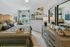 Modern bedroom featuring a large bed with neutral bedding, matching nightstands, a dresser with decorative accents, and open views into a connected living space.