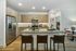Contemporary kitchen with stainless steel appliances, light wood cabinetry, a large island with barstool seating, and recessed lighting.