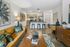 Living room with a comfortable sofa, coffee table, decorative accents, and a view into a modern kitchen with barstools and pendant lighting.