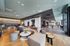 A spacious, modern resident lounge featuring contemporary sofas and armchairs, large windows that flood the room with natural light, wooden flooring, and a warm, inviting color palette that creates a cozy yet stylish atmosphere.