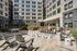 Modern outdoor courtyard with lounge seating, fire pits, and surrounding apartment buildings.