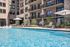 Elegant outdoor pool with chic loungers, shaded umbrellas, and upscale apartment balconies.