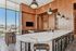 Sophisticated community kitchen featuring a spacious marble island, sleek wood cabinetry, stainless steel appliances, and panoramic city views through floor-to-ceiling windows.