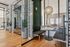 Refined co-working lounge with glass-walled private booths, plush seating, rich wood flooring, and artistic lighting for a productive yet elegant atmosphere