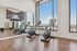 Sleek fitness studio featuring modern cardio equipment, expansive floor-to-ceiling windows, and stunning skyline views for an energizing workout experience.