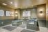 Modern pet grooming spa with green-tiled wash stations, wall-mounted sprayers, and large dog portraits on the walls.