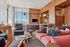A modern resident lounge with large windows, comfortable seating including blush sofas and navy chairs, a large TV, and wood-accented shelving for a warm, inviting atmosphere.