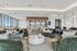 Elegant sky lounge with velvet green sectionals, marble coffee table, designer lighting, and a stylish kitchen bar.