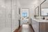 Bright, spa-like bathroom featuring a glass-enclosed shower, large soaking tub, double vanity, and modern finishes.