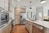 Contemporary kitchen featuring stainless steel appliances, a center island with a sink, pendant lighting, and light wood cabinetry with modern finishes.