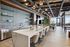 Chic resident lounge with a large marble island, designer barstools, open shelving with glassware, and contemporary lighting in a stylish indoor setting.