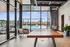 Indoor ping pong table set near floor-to-ceiling windows overlooking a rooftop pool and city skyline, surrounded by modern seating.