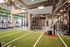 Spacious, modern gym featuring turf lanes, free weights, resistance machines, and floor-to-ceiling windows for natural light.