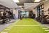 Modern fitness center featuring indoor turf lanes, stair climbers, free weights, squat racks, kettlebells, and functional training equipment.