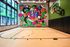 Modern indoor basketball court with hardwood flooring and a large colorful mural featuring abstract characters and basketballs on the far wall.