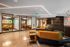 Stylish coworking lounge with mustard yellow meeting rooms, cozy modern sofas, and bold overhead lighting.