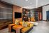 Contemporary lounge with mustard yellow seating, bold accent pillows, modern wall paneling, and mounted TV.