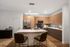 Spacious apartment kitchen with wood cabinetry, black appliances, and a white center island with two bar stools.