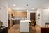 Contemporary kitchen with wood cabinetry, stainless steel appliances, and a central island featuring seating for two, under soft recessed lighting.