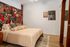 Bedroom featuring a bold, colorful graffiti-style accent wall, neutral bedding with textured pillows, modern artwork, and hardwood floors.