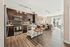 Open-concept kitchen with stainless steel appliances, dark wood cabinets, backsplash tile, and an island with bar seating.