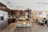 Open-concept kitchen with dark wood cabinetry and stainless steel appliances flowing into a modern living room with stylish decor.