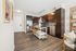Open-layout kitchen with dark cabinetry, stainless steel appliances, center island, and view into cozy living area.