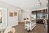 Modern kitchen with center island, dark cabinets, stainless steel applicanes, and view into hallway.