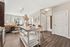 Bright kitchen, with central white island, wood flooring, bar seating, and hallway access to rooms.