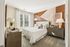 Chic bedroom with large bed, modern decor, and natural light.