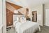 Bedroom with queen bed, accent wall, and carpeted flooring.