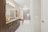 Modern bathroom with a granite countertop, dark wood vanity, large mirror, and a bathtub with gray tile surround and a white-and-orange ombr&eacute; shower curtain.