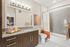 Contemporary bathroom with granite countertops, a dark wood vanity, a large mirror, and a bathtub with gray tile and a white-and-orange ombr&eacute; shower curtain.