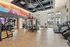 Spacious modern gym with colorful mural and various exercise equipment in a bright, open space.