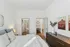 Elegant bedroom with plush bedding, modern furniture, and a view into an adjacent bathroom and study nook.