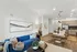 Inviting open-concept living space with a blue velvet sofa, modern kitchen, and elegant dining area.