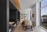 Modern office area with large windows, stylish wood table, and cozy booth seating.